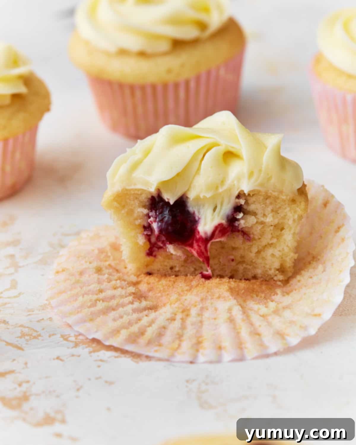 A perfectly frosted berry filled cupcake, showcasing the vibrant berry center and creamy vanilla mascarpone frosting.