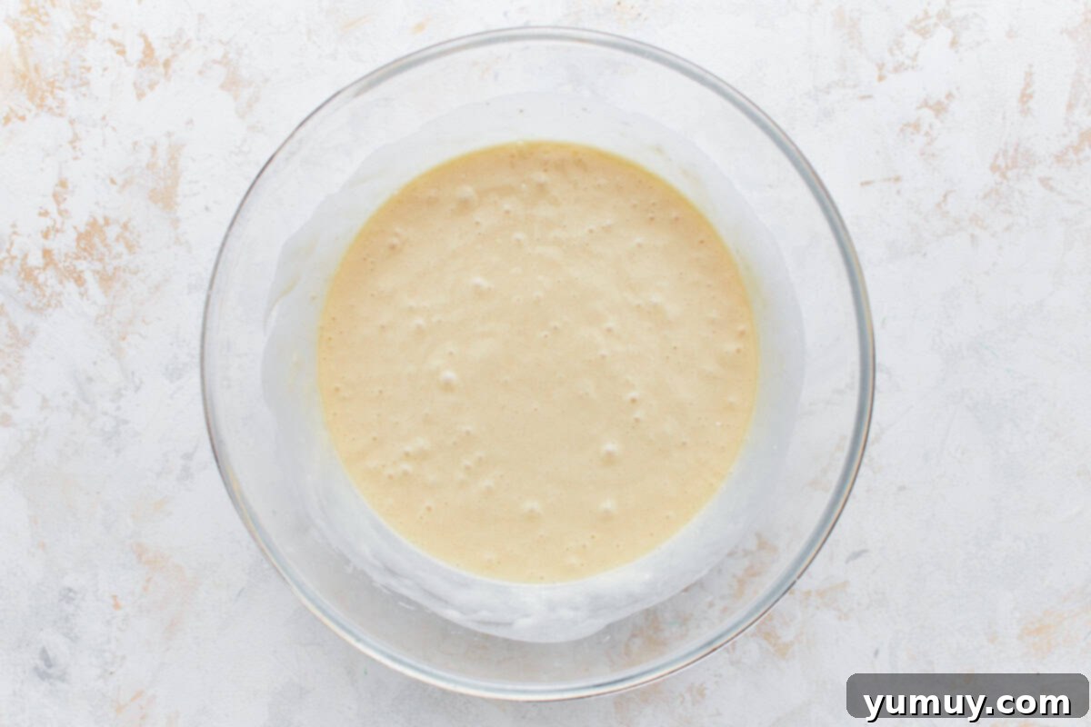Smooth cupcake batter in a clear glass mixing bowl, ready for the cupcake tin.