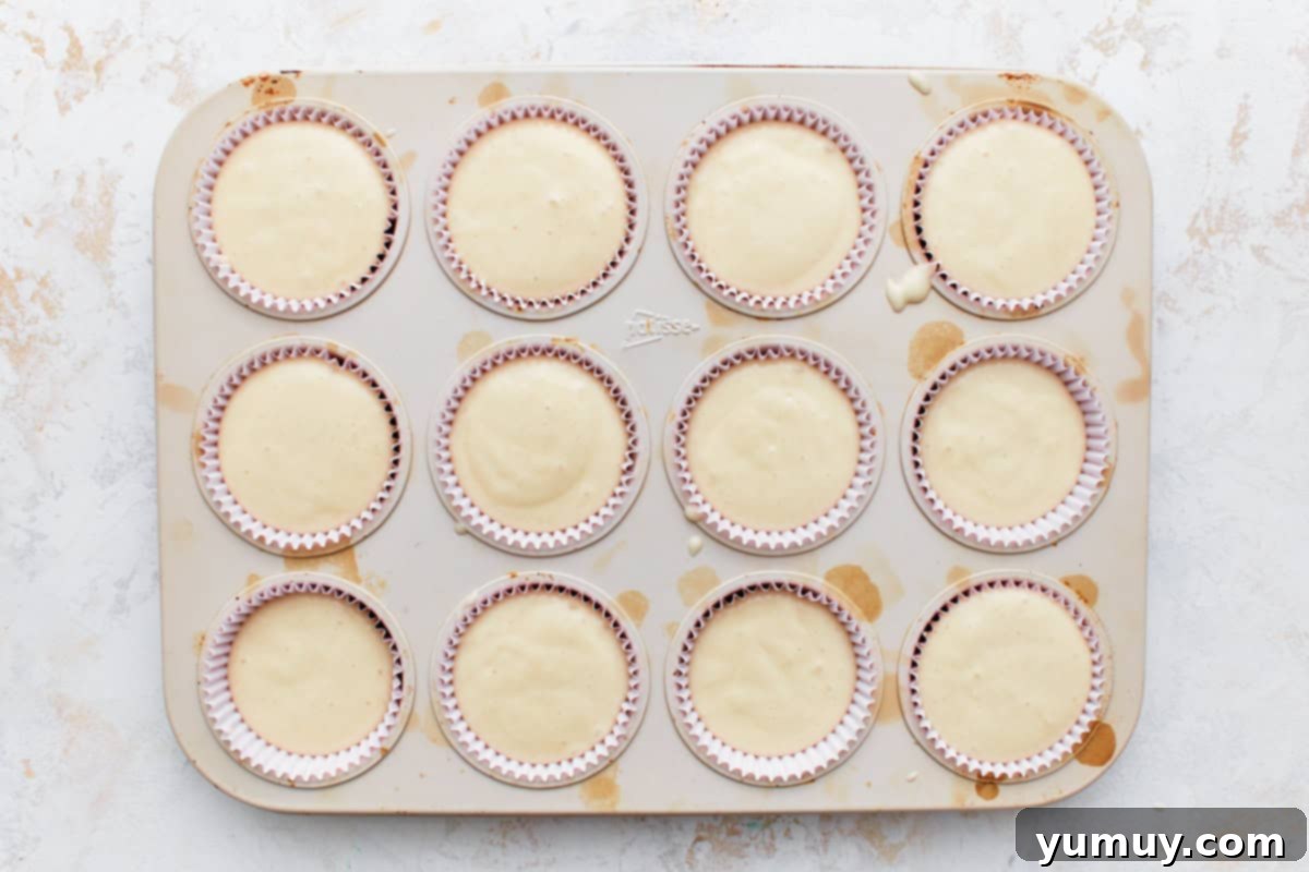 A cupcake tin precisely filled with an even amount of batter in each liner.