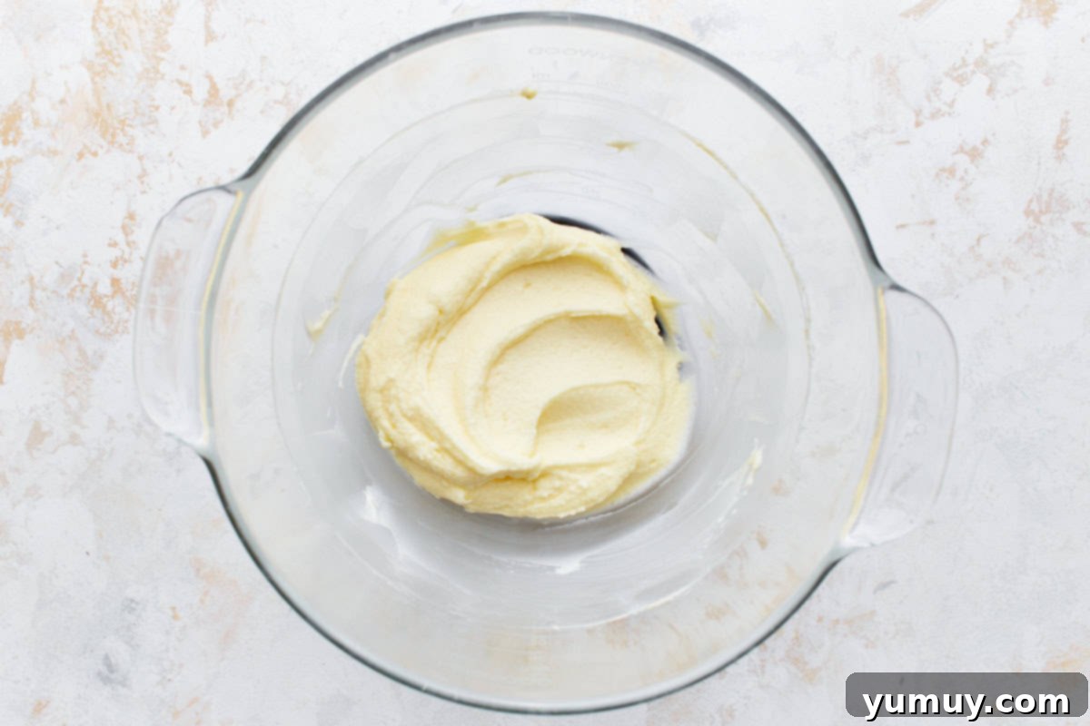 Creamy vanilla mascarpone frosting being whipped in a stand mixer bowl.