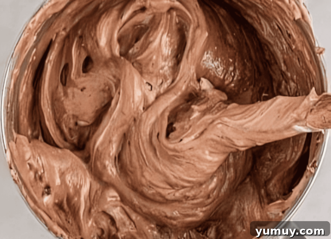 Light & Airy Chocolate Cloud Cake 19 folding chocolate meringue in a stainless mixing bowl.