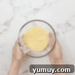Boston Cream Delights 13 Pastry cream covered with plastic wrap pressed to the surface, cooling in a glass bowl.