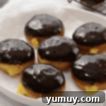 Boston Cream Delights 16 A tray of freshly glazed Boston Cream Donuts, glistening with chocolate.