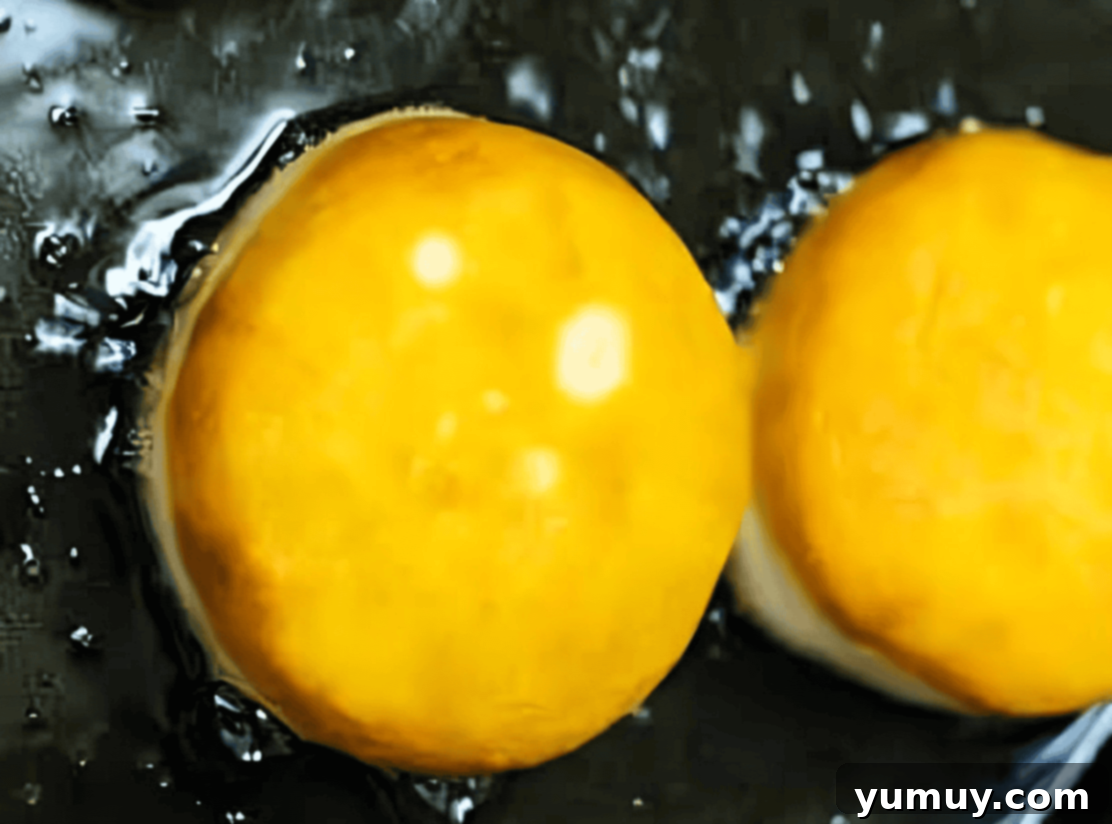 Boston Cream Delights 22 Three donuts frying to a golden brown in hot oil in a Dutch oven.