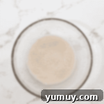 Boston Cream Delights 6 Proofing yeast in a glass bowl, showing active foam on the surface.