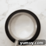 Boston Cream Delights 11 Milk, sugar, and cornstarch being whisked in a saucepan on the stovetop.