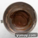 powdered sugar and cocoa added to no bake chocolate cheesecake batter in a stainless mixing bowl.