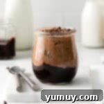 side view of a no bake chocolate cheesecake cup on a marble cutting board with spoons.