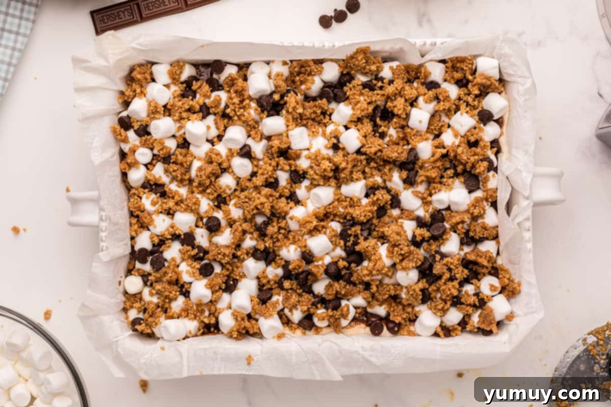 Smores Bars 21 crumbled graham crackers, mini marshmallows, and chocolate chips in a baking pan.