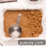 Smores Bars 8 pressing graham cracker crust into a baking pan with a measuring cup.