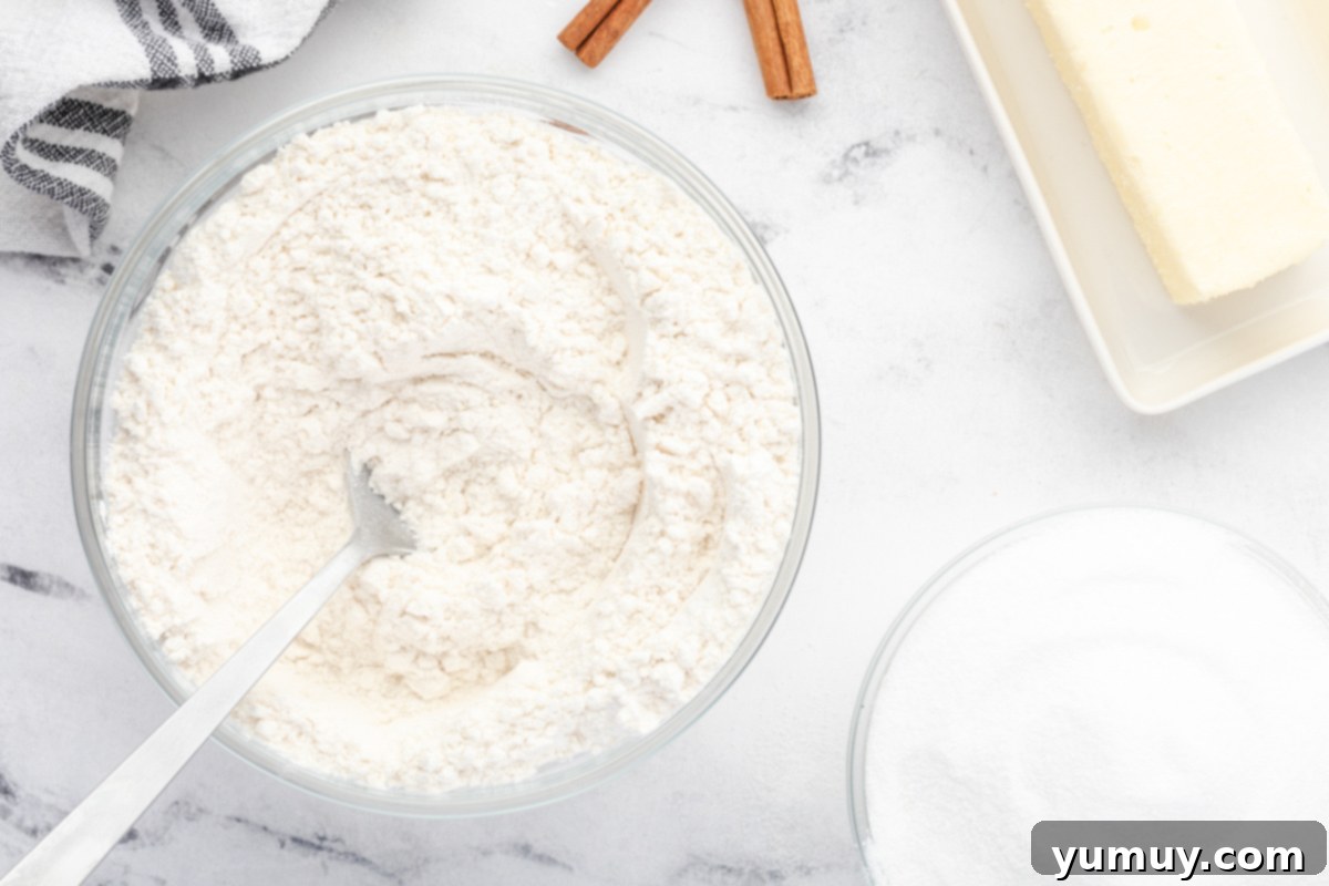a bowl of flour, sugar and cinnamon next to a spoon.