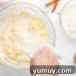 pouring buttermilk into cupcake batter in a glass bowl.