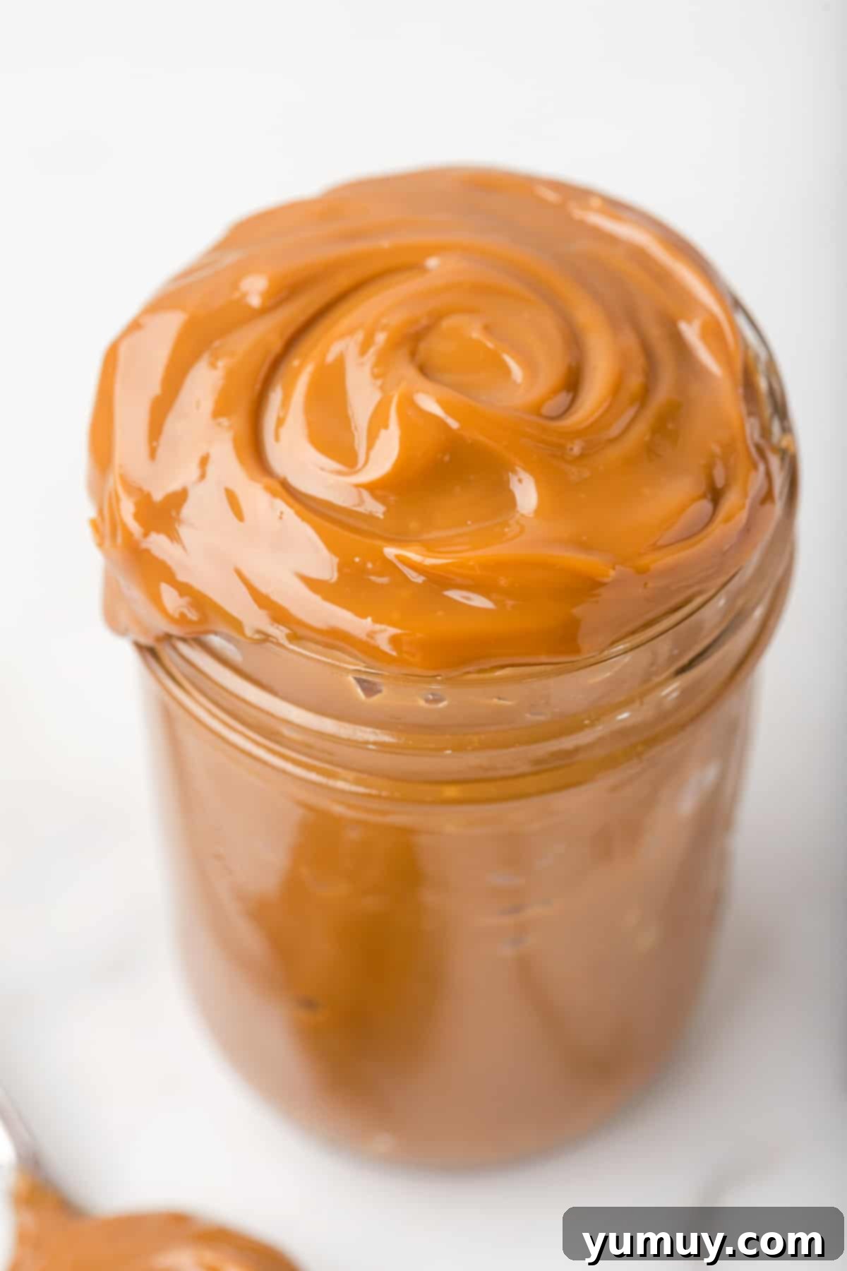 Perfect Homemade Dulce de Leche 2 A beautiful jar of rich, homemade dulce de leche, showcasing its thick, golden-brown texture.
