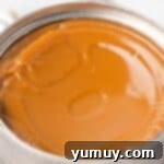 Perfect Homemade Dulce de Leche 7 A sealed can of dulce de leche cooling down after simmering, with a rich caramel color visible through the can.