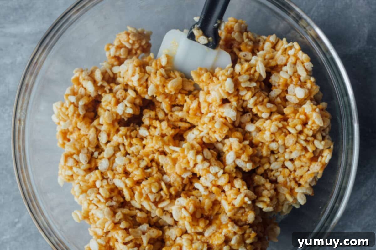 A bowl of Rice Krispies cereal with a spatula, ready to be mixed with the peanut butter syrup.