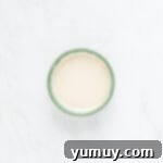 A bowl of smooth vanilla glaze, ready for dipping French crullers.