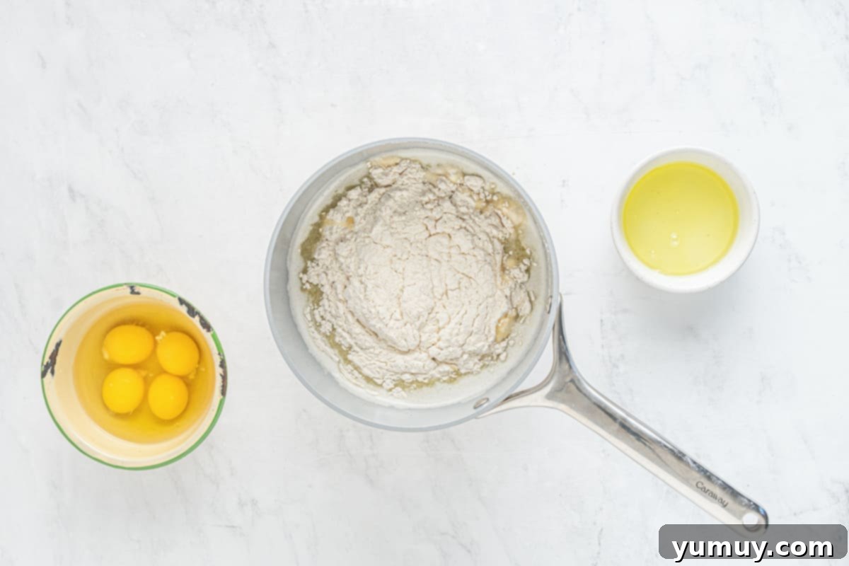 A bowl of flour, eggs, and butter ready to be mixed for French crullers on a marble table.