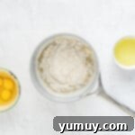 Ingredients for French Crullers including flour, eggs, and butter, laid out on a marble counter.