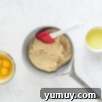 Mixing bowl with choux pastry ingredients including eggs and butter, ready for preparation.