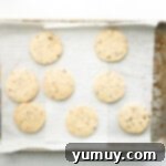 Melt-in-Your-Mouth Pecan Shortbread 5 freshly baked pecan shortbread cookies on a lined baking sheet.