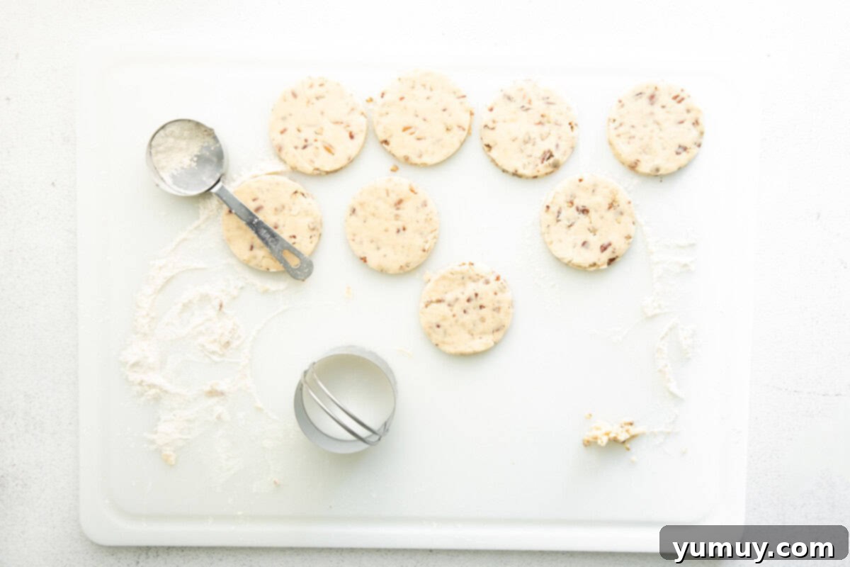 Melt-in-Your-Mouth Pecan Shortbread 6 cut out pecan shortbread cookies on a floured cutting board.