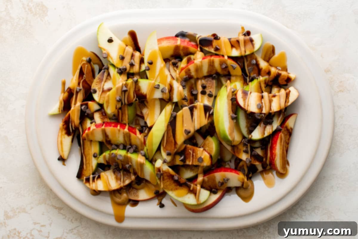 A complete platter of irresistible caramel apple nachos, adorned with sweet caramel, rich chocolate sauce, and a generous scattering of mini chocolate chips, ready for serving.