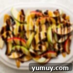 Apple slices beautifully arranged on a platter, being drizzled with rich caramel and chocolate sauces.
