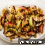 A complete platter of irresistible caramel apple nachos, adorned with sweet caramel, rich chocolate sauce, and a generous scattering of mini chocolate chips, ready for serving.