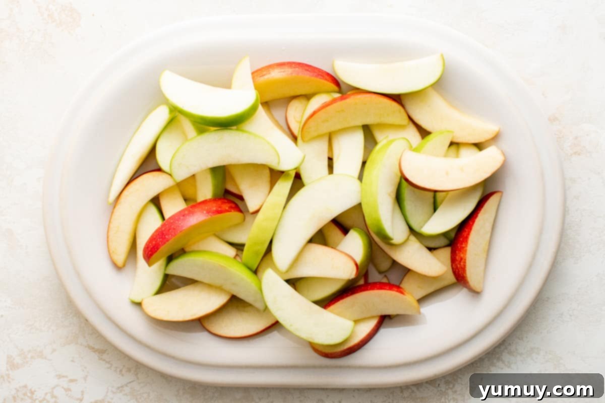 A colorful assortment of perfectly cut green and red apple slices, drained and ready for their sweet toppings.