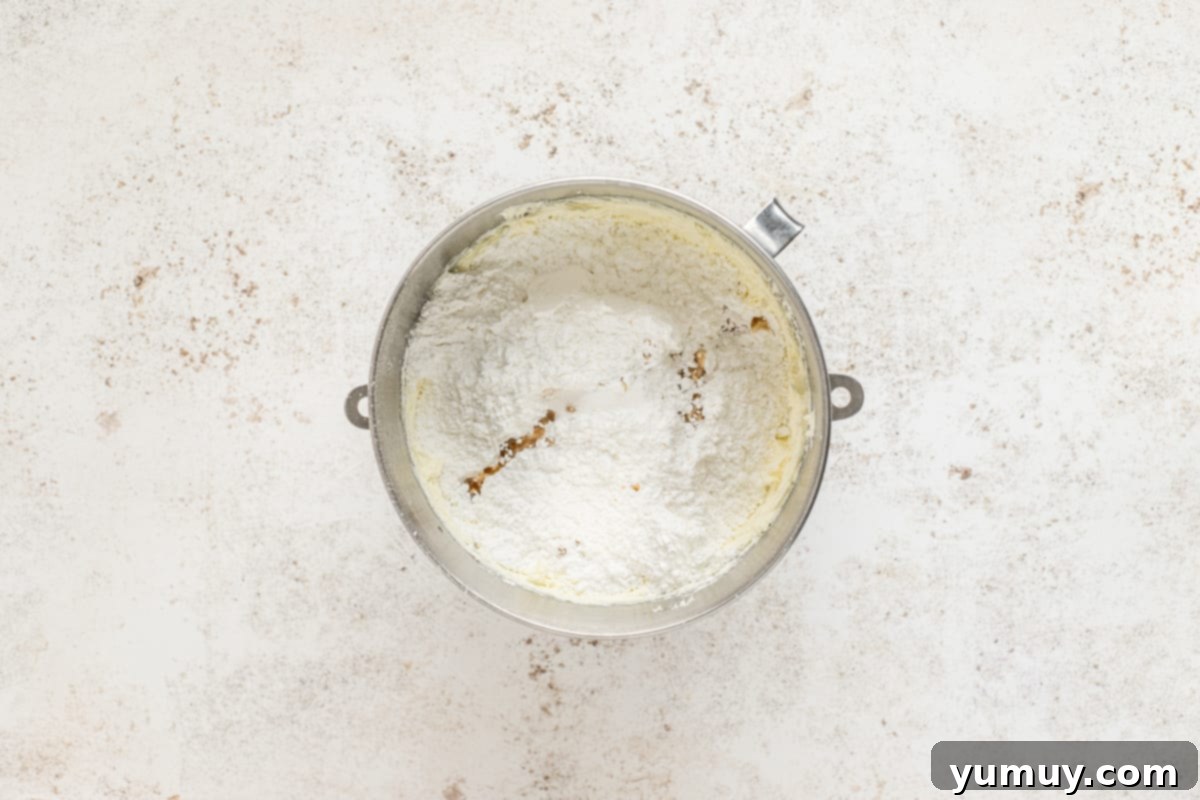 Irresistible Pumpkin Cake with Zesty Cream Cheese Frosting 17 flour in a metal bowl on a white background.