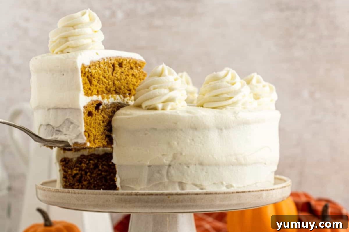 Irresistible Pumpkin Cake with Zesty Cream Cheese Frosting 3 side view of a cake server removing a slice of pumpkin cake from a cake on a cake stand.