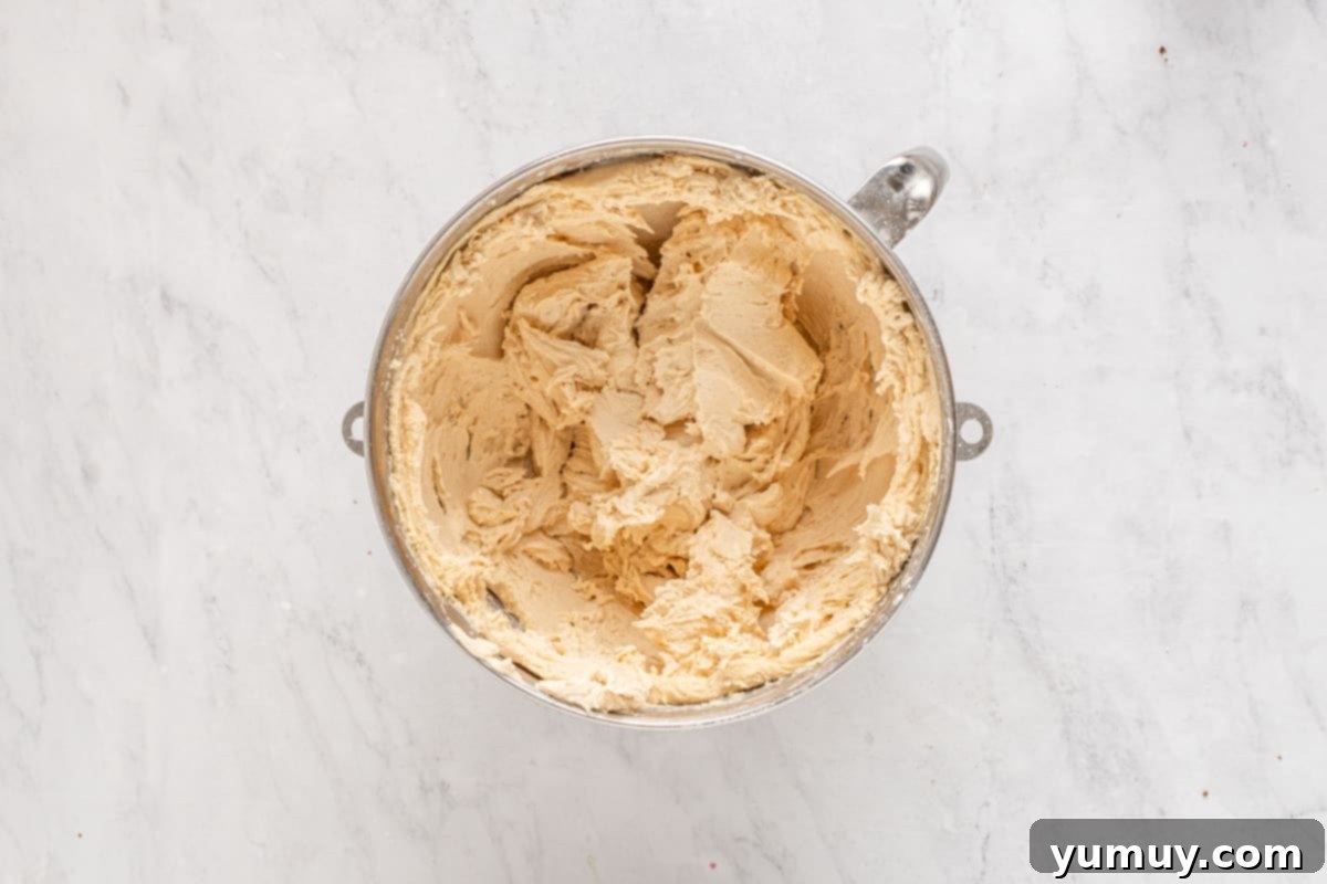 Creamy peanut butter frosting being mixed in a stand mixer bowl.
