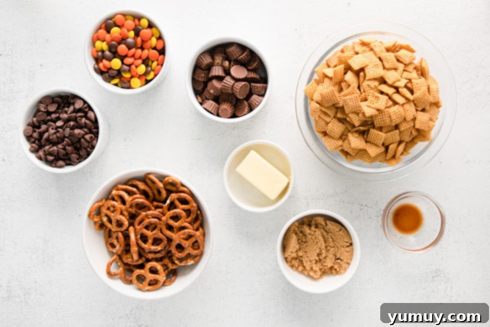 A selection of ingredients for Chex mix laid out on a clean surface, including cereal, pretzels, and various candies.