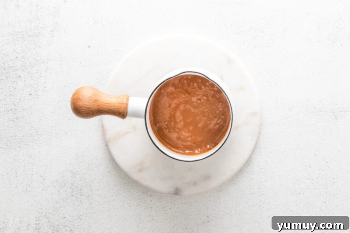 Caramel Chocolate Shortbread Cookies 17 Lush, melted caramel sauce pooling in a small saucepan, ready to fill the cookies.