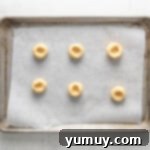 Caramel Chocolate Shortbread Cookies 7 Six unbaked shortbread cookie dough balls with thumbprint indentations on a baking sheet.