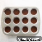 chocolate cupcake batter in the wells of a cupcake tin.