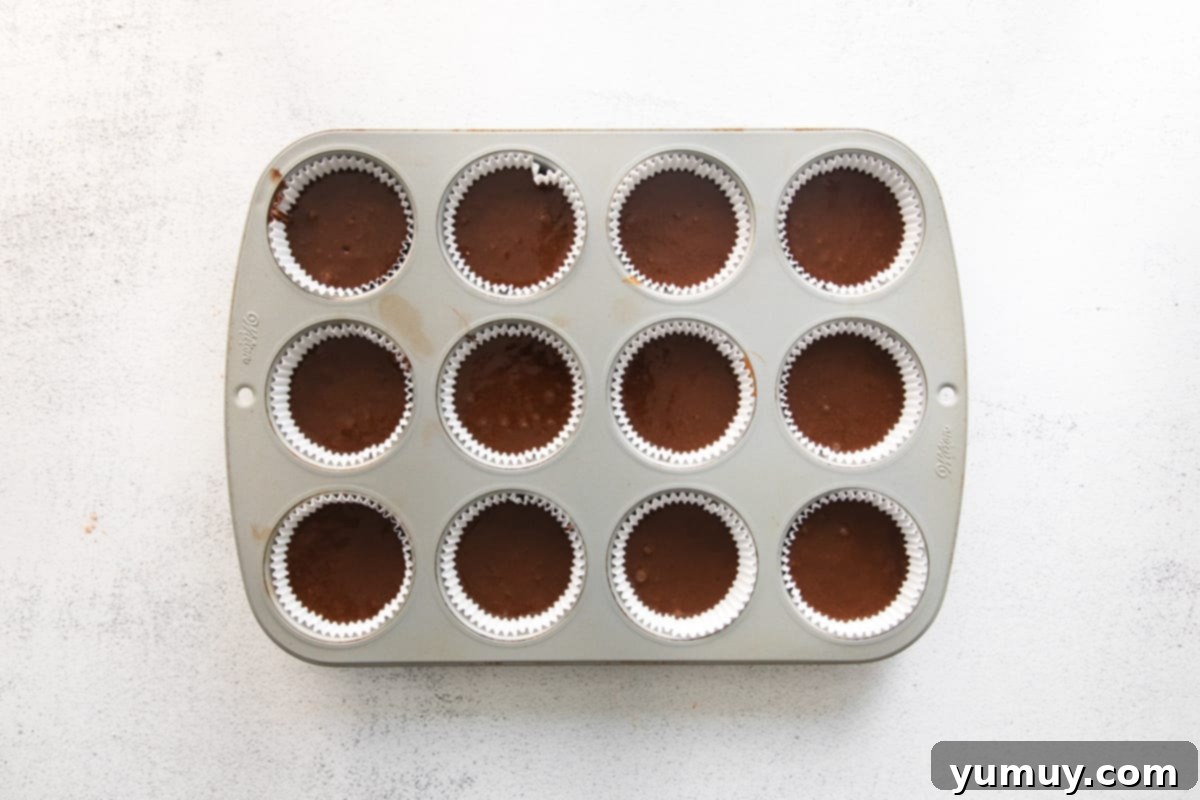 chocolate cupcake batter in the wells of a cupcake tin.