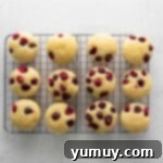 Tangy Cranberry Delights 11 Overhead view of unfrosted cranberry cupcakes lined up on a cooling rack.