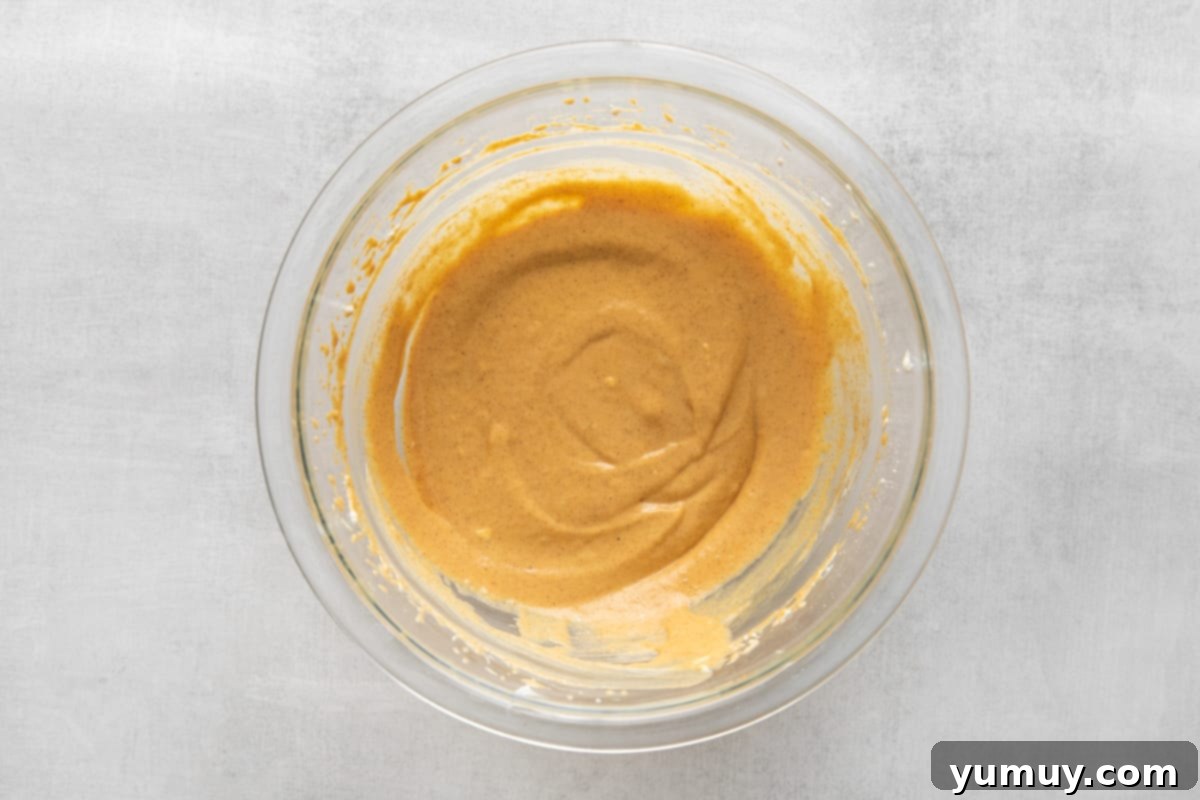 The pumpkin pie filling, after being thoroughly beaten, showing its light and fluffy texture in a mixing bowl.