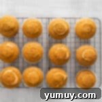Cored cupcakes lined up on a cooling rack, showing how to prepare them for filling.