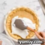 Golden Butterscotch Delight 13 Spreading fluffy meringue evenly over a butterscotch pie filling.