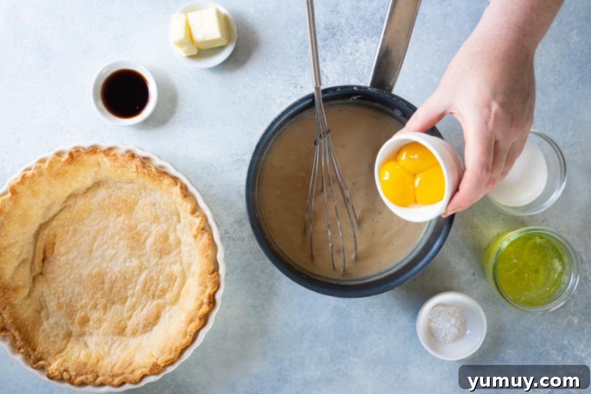 Golden Butterscotch Delight 18 Beaten egg yolks being carefully poured into the warm butterscotch mixture in a saucepan, with a whisk ready to stir.