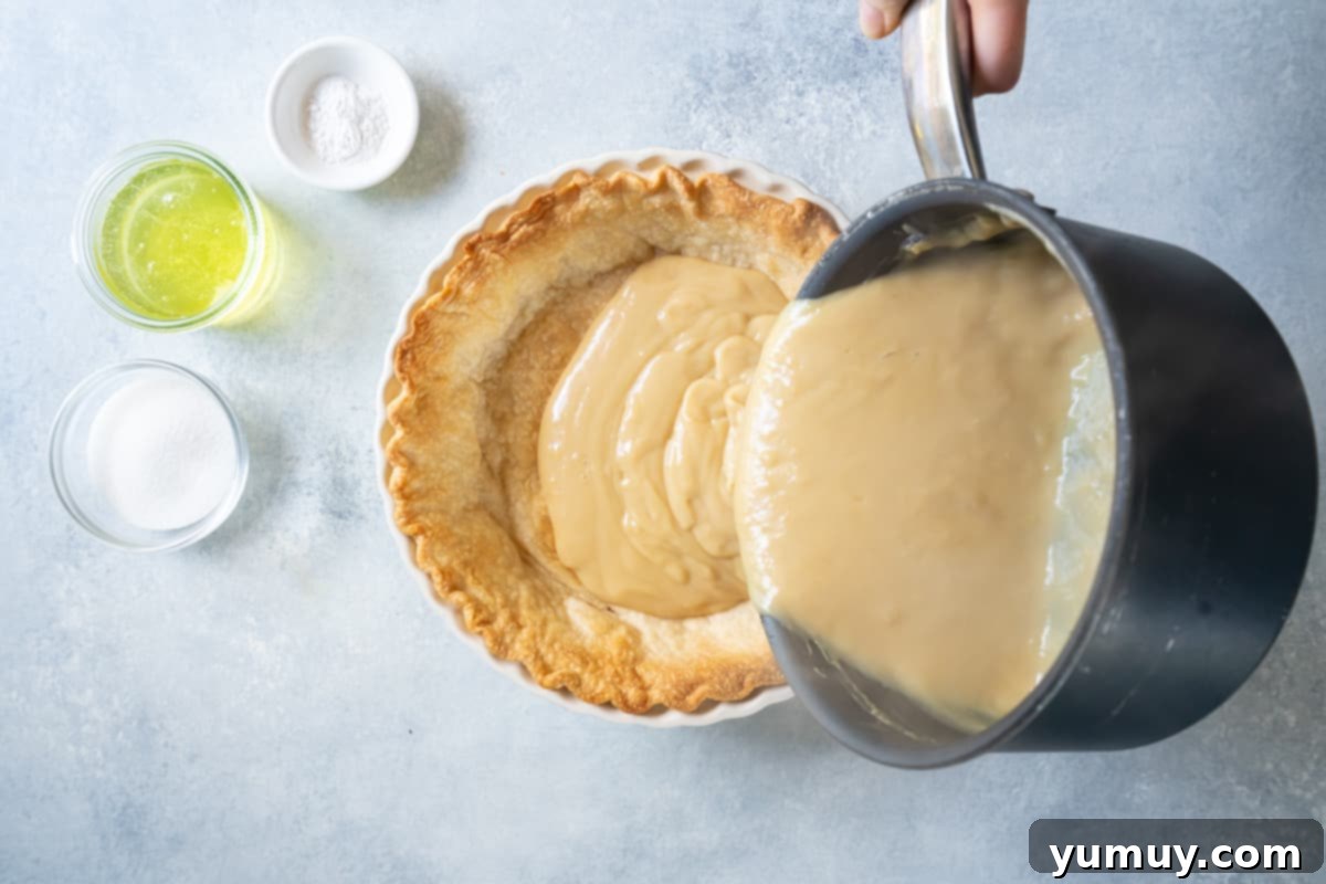 Golden Butterscotch Delight 20 The smooth butterscotch pudding filling being poured into a pre-baked pie crust, filling it perfectly.