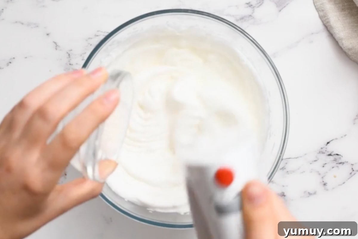 Golden Butterscotch Delight 22 The stand mixer whisking egg whites as granulated sugar is slowly poured in, creating shiny meringue.