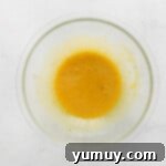 Decadent Chocolate Custard 6 a bowl filled with a yellow liquid on a white background.