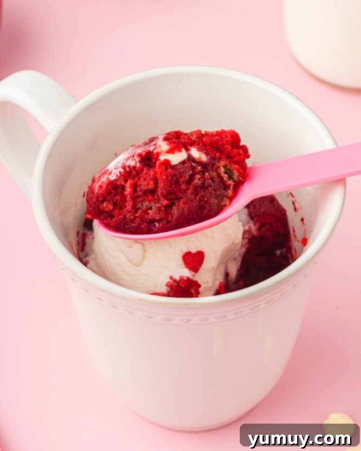 Spoon scooping out a bite of red velvet mug cake, showcasing its moist texture and vibrant color.