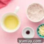 dry ingredients in a bowl next to bowls of oil, food coloring, and white chocolate chips.