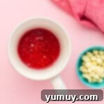 red velvet cake batter in a mug next to a bowl of white chocolate chips