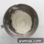 Indulgent Homemade Red Velvet Cupcakes 11 whipped cream in a metal mixing bowl on a white background.