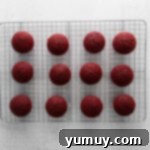 Indulgent Homemade Red Velvet Cupcakes 9 red velvet cupcakes lined up on a cooling rack